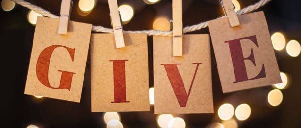 Give Concept Clipped Cards and Lights The word GIVE spelled out on clothespin clipped cards in front of glowing lights.